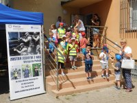 Dzieci wychodzą z budynku komendy ze słodyczami i lodami. Po lewej stronie zdjęcia baner promujący prace w Policji - Zostań Jednym z Nas.