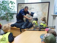 Pod nadzorem policjanta, dzieci przymierzają hełm ochronny.