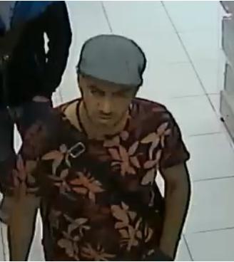 Wizerunek mężczyzny - sprawca kradzieży. Ubrany w koszulkę koloru brązowego w jase duże kwiaty. Na głowie czapka typu beret koloru szarego.