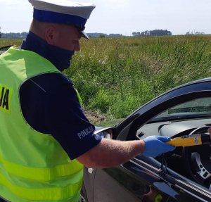 Policjant Wydziału Ruchu Drogowego podczas sprawdzania stany trzeźwości kierowcy siedzącego w pojeździe.