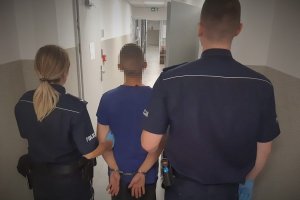 Umundurowani policjanci wraz z zatrzymanym podczas doprowadzenia do Pomieszczenia dla Osób Zatrzymanych w budynku Komendy Powiatowej Policji w Zambrowie.