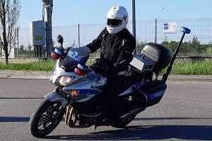 Umundurowany funkcjonariusz Wydziału Ruchu Drogowego podczas jazdy motocyklem policyjnym.