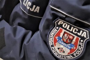 Naszywka z logo i napisem POLICJA - ZAMBRÓW, na ramieniu kurtki w kolorze granatowym.