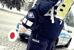 policjant na zewnatrz; obok radiowozu; trzyma tarczę do zatrzymywania pojazdów