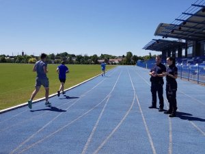 Policjanci stojący na stadionie i klaszczący dla biegnących uczniów.