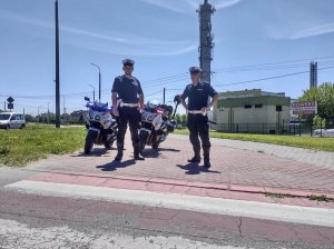 Policjanci stojący przed przejściem dla p[pieszych z tyłu policyjne motory.