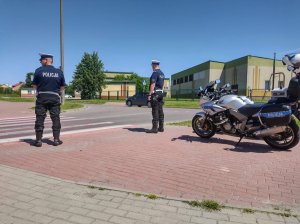 Policjanci przed przejściem dla pieszych,z a nimi motory policyjne. Zdjęcie robione  z tyłu.