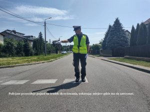 Policjant podczas kierowania ruchem Na dole napis: Policjant przywołuje pojazd na środek skrzyżowania, wskazując miejsce gdzie ma się zatrzymać.