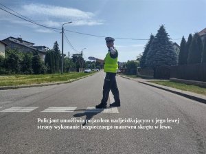 Policjant podczas kierowania ruchem. Na dole napis: Policjant umożliwia pojazdom nadjeżdżającym z jego lewej strony wykonanie bezpiecznego manewru skrętu w lewo.