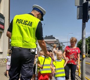 Policjant rozdaje przedszkolakom odblaski.