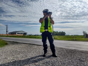 Policjant stojący na poboczu podczas pomiaru prędkości.