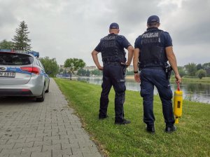 Policjanci podczas kontroli zbiornika wodne, który jest w tle.