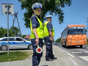 Policjanci ruchu drogowego podczas służby. w tle jezdnia oraz autobus.