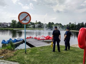 Policjanci stojący przed akwenem wodnym, w tle zalew oraz kajaki.