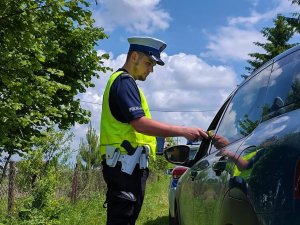 Umundurowany policjant podczas badania stanu trzeźwości urządzeniem alkoblow.