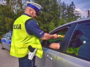 Policjant podczas kontroli drogowej bada stan trzeźwości kierującego samochodem.