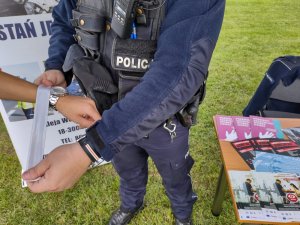 Policjant zakładający odblask na dłoń osoby.