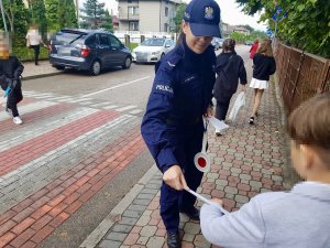 Umundurowana policjantka zakładając dziecku odblask na nadgarstek.