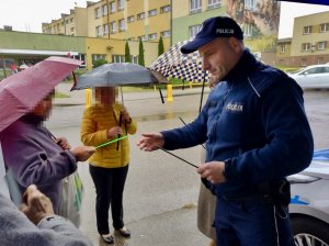 Umundurowany policjant rozdaje odblaski.