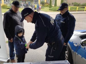 Policjant zakłada dziecku na rękę odblask.