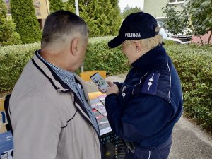 Policjanta podczas przedstawiania Krajowej Mapy Zagrożeń bezpieczeństwa na telefonie.