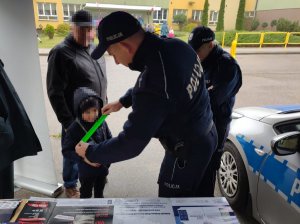 Policjant zakłada dziecku na rękę odblask.