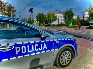 Radiowóz policyjny stojący przed przejściem dla pieszych w centrum miasta.