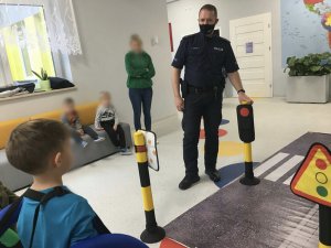 Policjant oraz profilaktyk w trakcie lekcji z przedszkolakami na temat bezpiecznej drogi do szkoły.