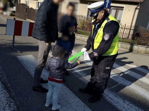 Policjanci ruchu drogowego podczas rozdawania dzieciom odblask na rękę.