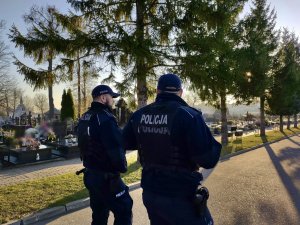 Umundurowani policjanci podczas patrolu na cmentarzu.