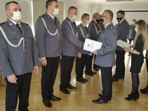 Komendant zambrowskiej jednostki wręczający policjantowi akt mianowania na wyższy stopień.