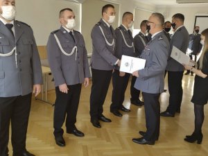 Komendant zambrowskiej jednostki wręczający policjantowi akt mianowania na wyższy stopień.