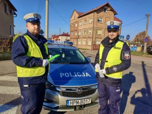 Policjanci ruchu drogowego w patrolu podczas patrolu, trzymający w dłoniach odblaski.