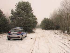 Radiowóz policyjny, a w tle las oraz leżący śnieg.