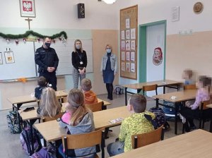 Policjant oraz profilaktyk podczas spotkania z uczniami w szkole.