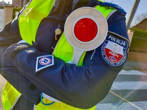 Policjant Wydziału ruchu drogowego trzyma w dłonie tarcze do zatrzymywania pojazdów.