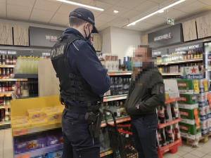 Policjant w sklepie podczas kontroli przestrzegania obostrzeń noszenia maseczki na ustach i nosie przez klienta.