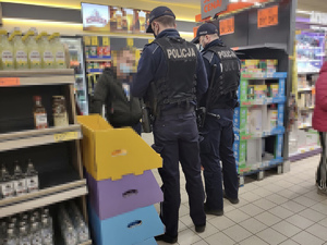 Policjanci w sklepie podczas kontroli przestrzegania obostrzeń noszenia maseczki na ustach i nosie przez klienta.