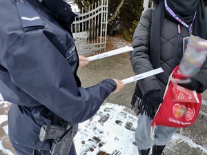 Policjantka podczas rozmów z wolontariuszami, rozdaje odblaski.