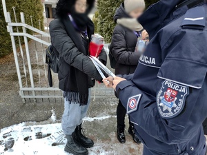 Policjantka podczas rozmów z wolontariuszami, rozdaje odblaski.