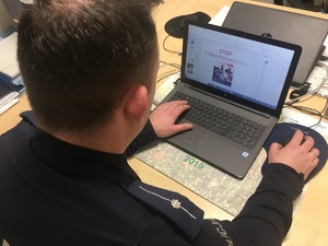 Policjant prowadzący lekcje online, przed nim stoi laptop.
