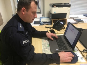 Policjant prowadzący lekcje online, przed nim stoi laptop.