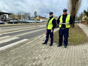 Policjanci podczas kontroli bezpieczeństwa pieszych stojąc na chodniku.