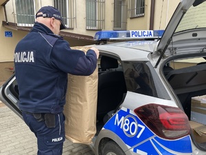 Policjant podczas pakowania do radiowozu paczek z żywnością dla obywateli Ukrainy.