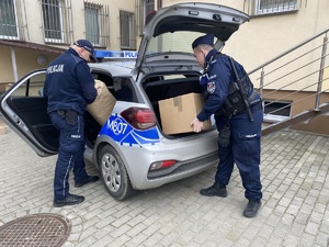 Policjanci podczas pakowania do radiowozu paczek z żywnością dla obywateli Ukrainy.