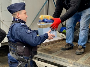Policjant podczas przekazywania paczek z żywnością dla obywateli Ukrainy.