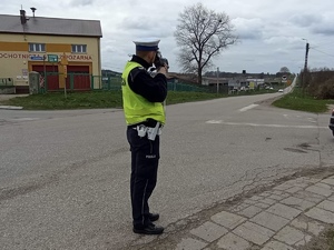 Policjant podczas kontroli prędkości, w tle jezdnia.