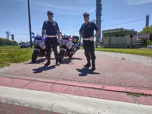 Policjanci w kombinezonach motocyklowych kontrolując rejon przejścia dla pieszych.