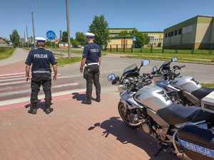 Policjanci w kombinezonach motocyklowych kontrolując rejon przejścia dla pieszych.