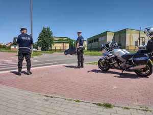 Policjanci w kombinezonach motocyklowych kontrolując rejon przejścia dla pieszych.
